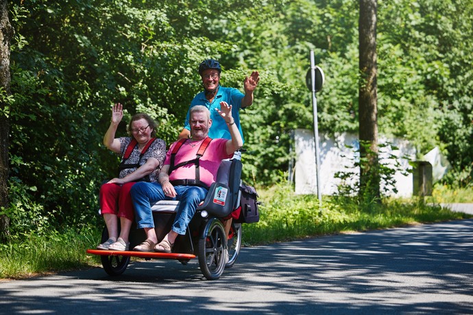 Zwei Personen werden in einer Rikscha durchs Grüne gefahren