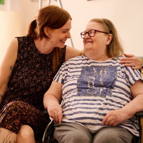 Eine Frau beugt sich zu einer anderen Eine Frau beugt sich zu einer anderen